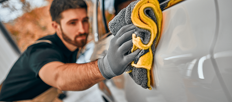 man cleaning vehicle before transport as part of his car shipping checklist